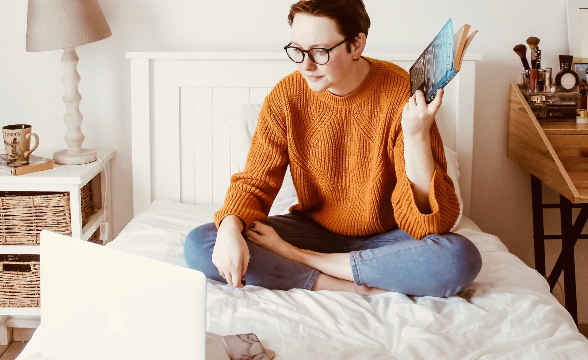 woman sitting on bed facing laptop